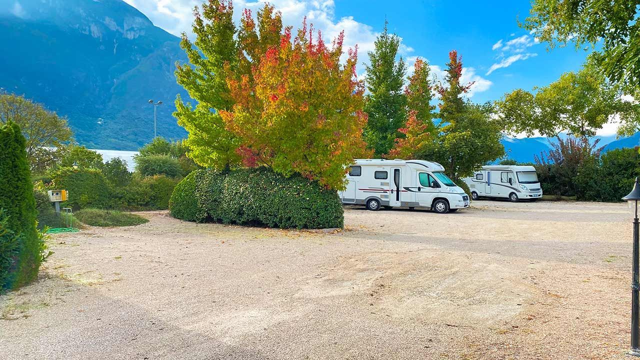 Camper nelle piazzole sotto gli alberi, con le montagne sullo sfondo